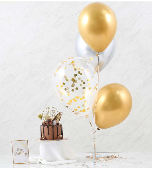 Chocolate ganache cake on gold stand with metallic balloons and Happy Birthday card for celebrations