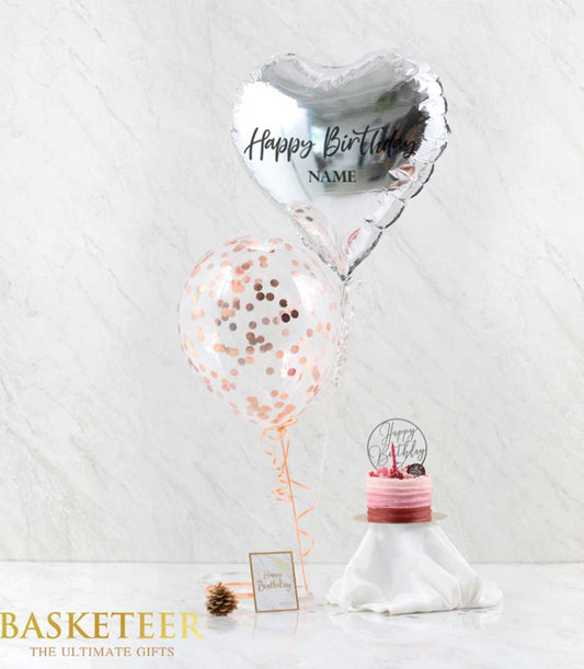 Gray heart balloon with rose gold confetti, pink tiered birthday cake, and greeting card gift set