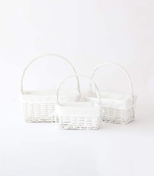 Three nested white wicker baskets with fabric liners and arched handles for premium gift presentation