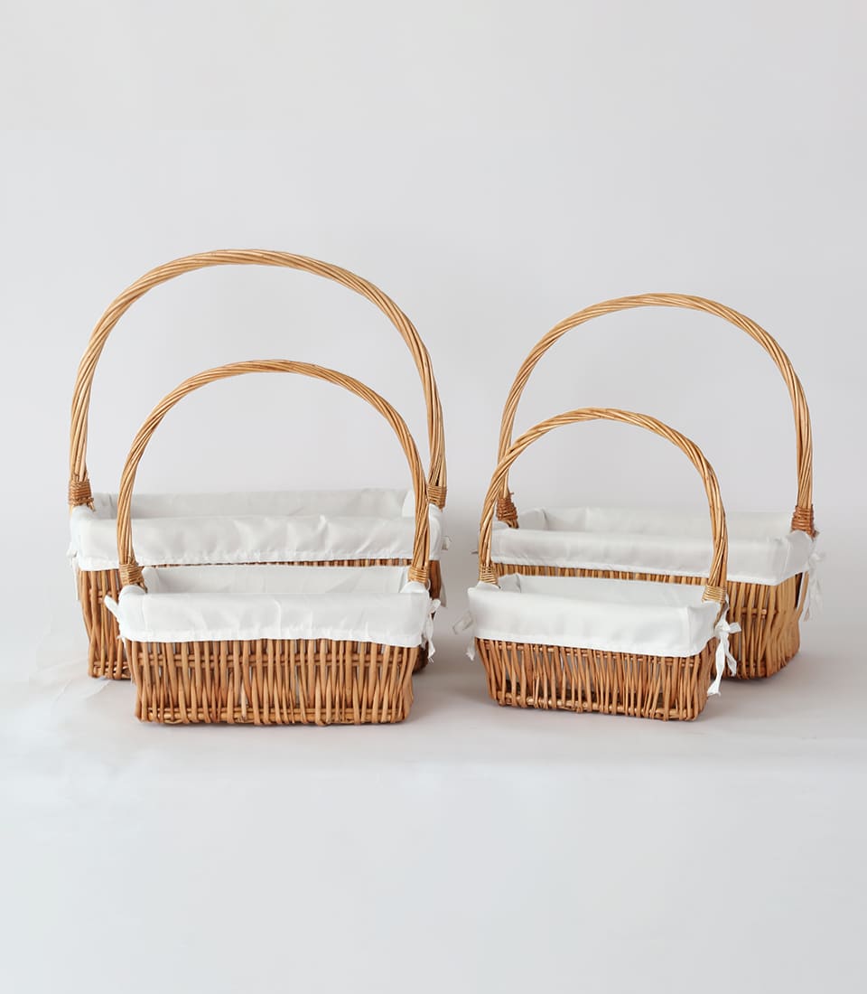 Nested woven storage baskets with white fabric linings and arched handles, natural light brown wicker set of four