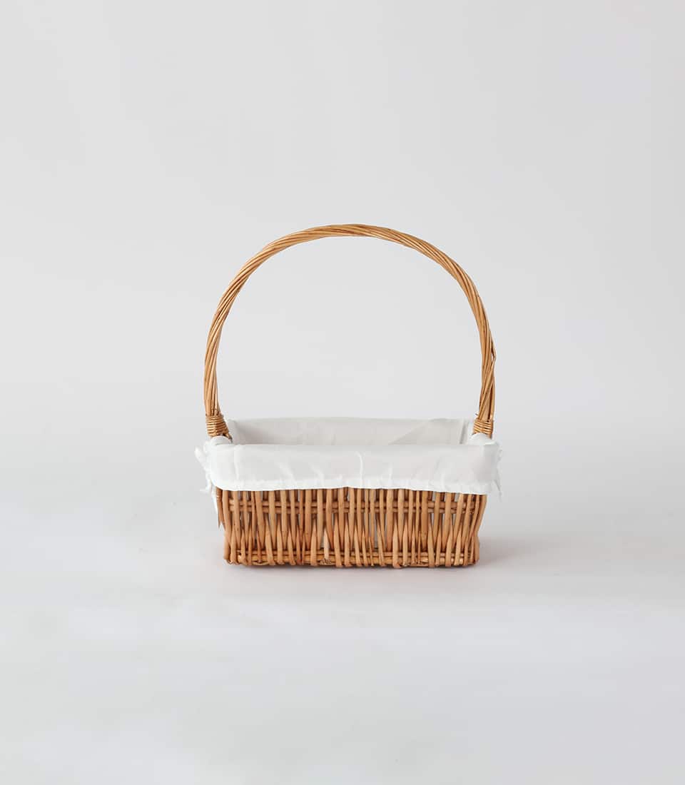 Light brown woven wicker basket with white cloth lining and arched handle