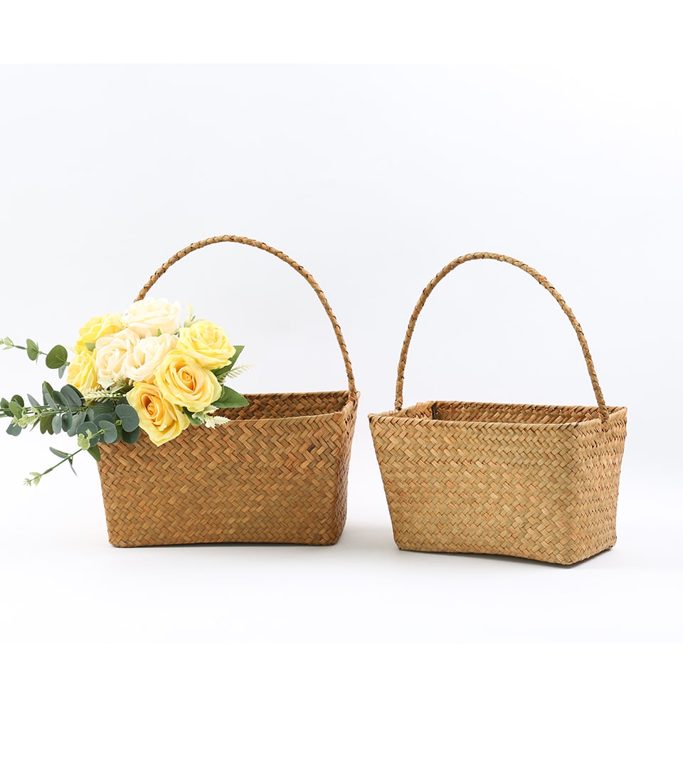 Woven straw gift baskets with braided handles, one filled with yellow and cream roses, one empty
