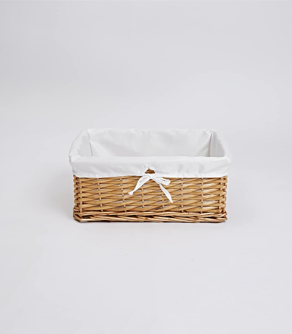 Light brown woven wicker basket with white fabric liner and ribbon bow