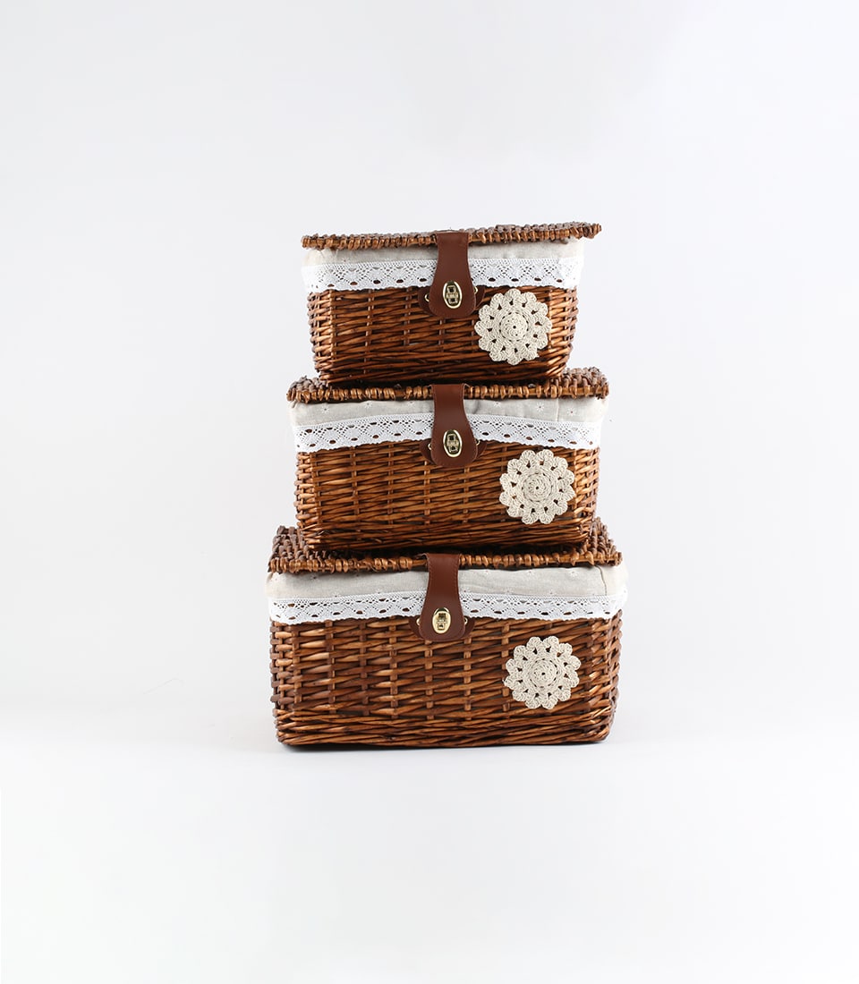 Tiered wicker baskets with white lace liners, leather straps, and crocheted floral details for luxury gift hampers
