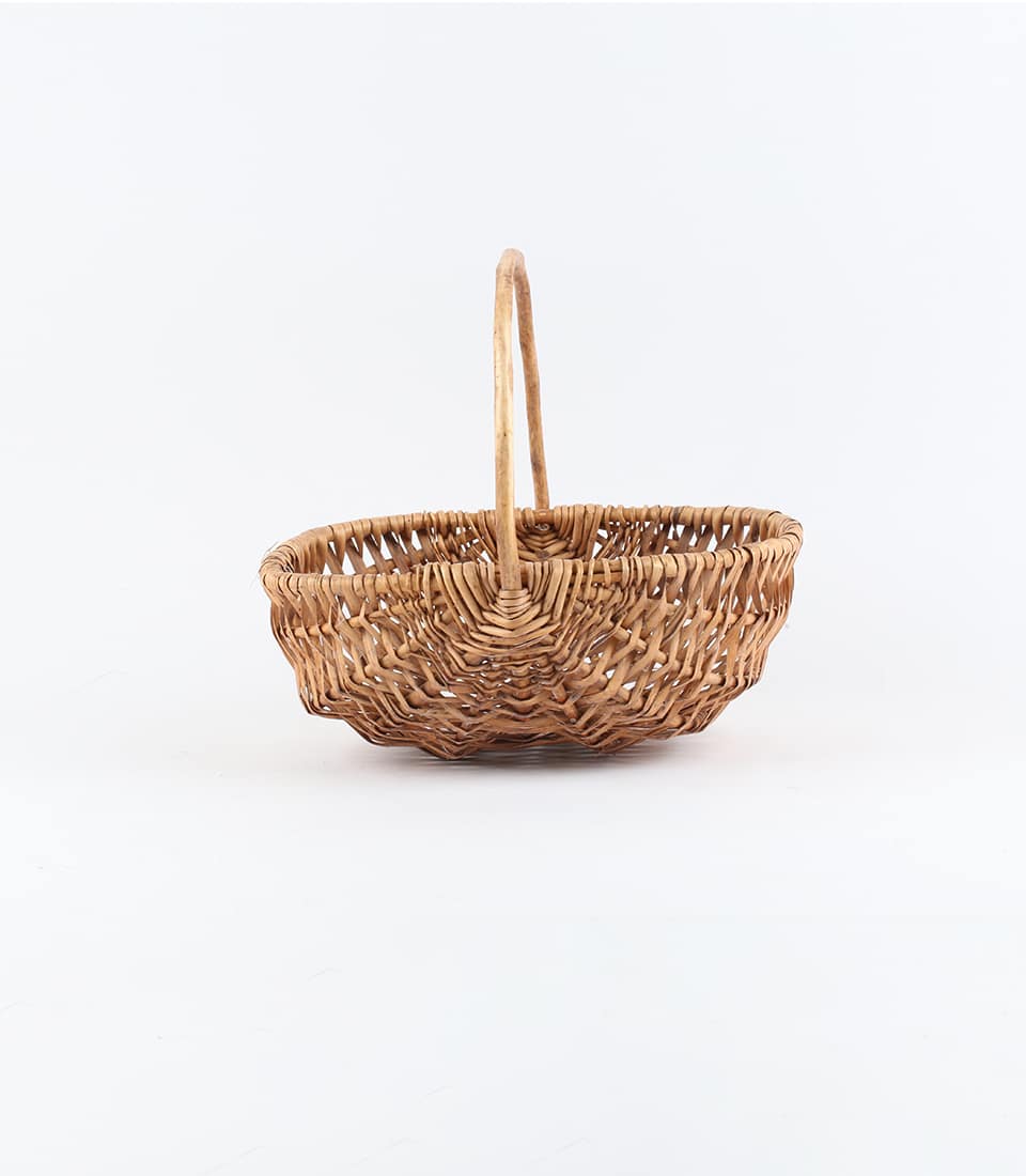 Light brown wicker basket with curved handle, artisan-crafted for luxury gift presentation