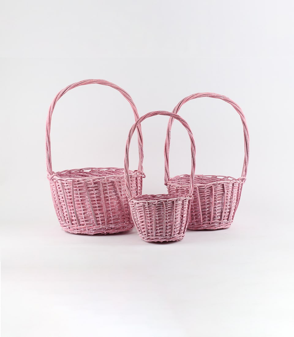 Light pink woven rattan baskets with arched handles, set of three sizes for gift hampers and artisan storage
