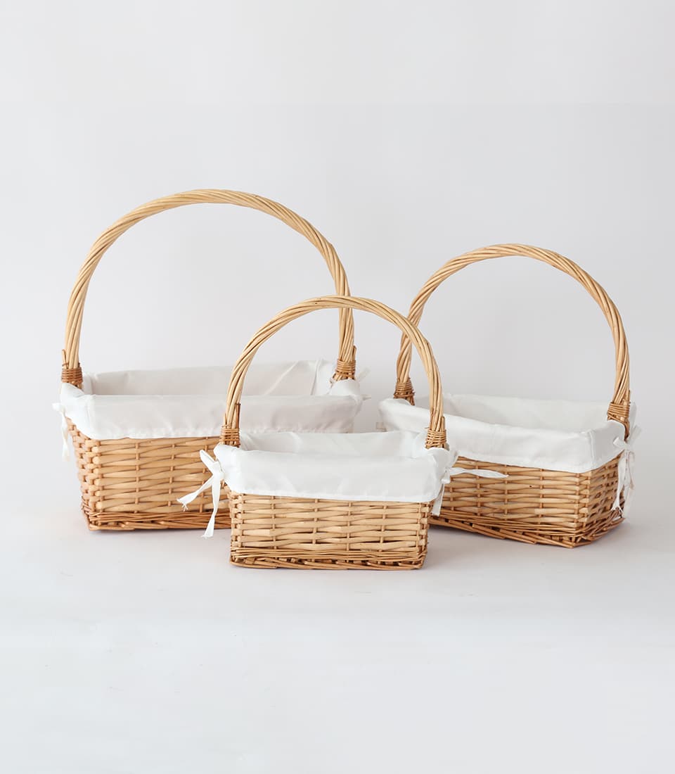 Three natural wicker baskets with white fabric liners and twisted handles, nested by size