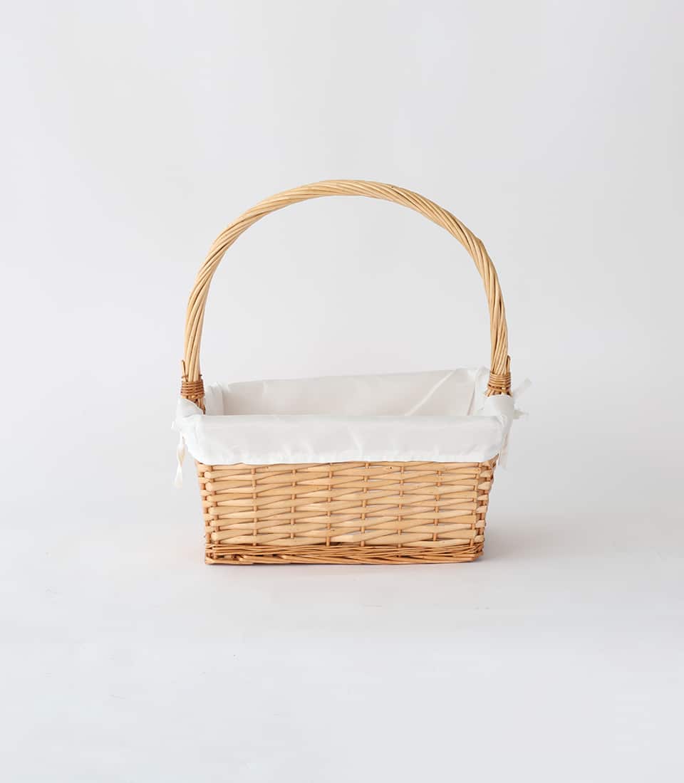 Light brown wicker gift basket with white fabric liner and handle bows