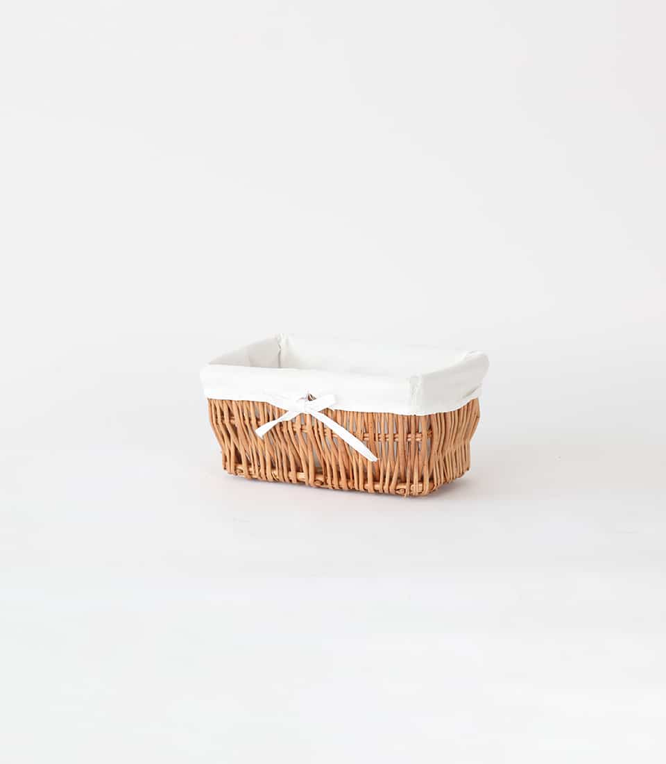 Light brown woven wicker storage basket with white fabric liner and ribbon bow