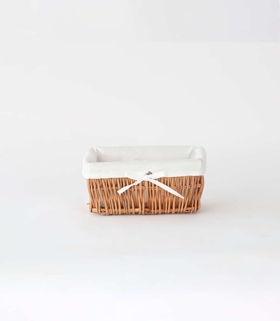 Light brown wicker storage basket with white fabric liner and ribbon bow