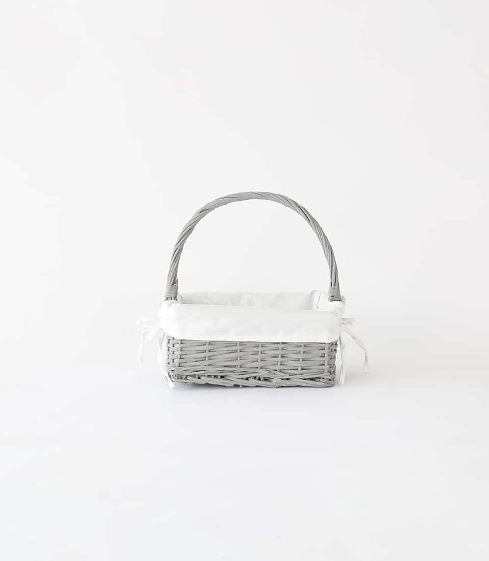 Light grey wicker gift basket with arched handle and white fabric liner