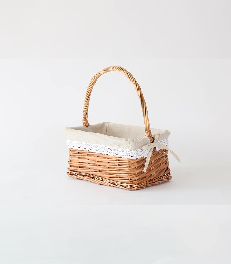 Light brown wicker basket with arched handle and cream lace-trimmed fabric lining for luxury gift presentation