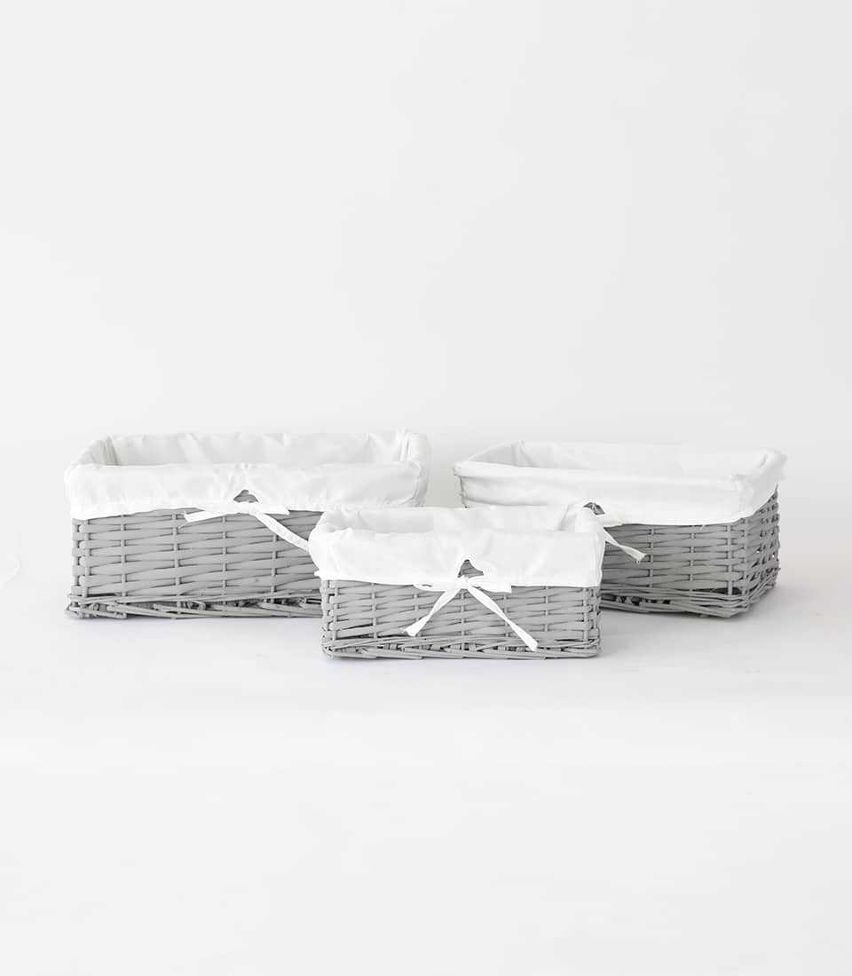 Grey woven wicker storage baskets with removable fabric liners and ribbon bows, set of three sizes