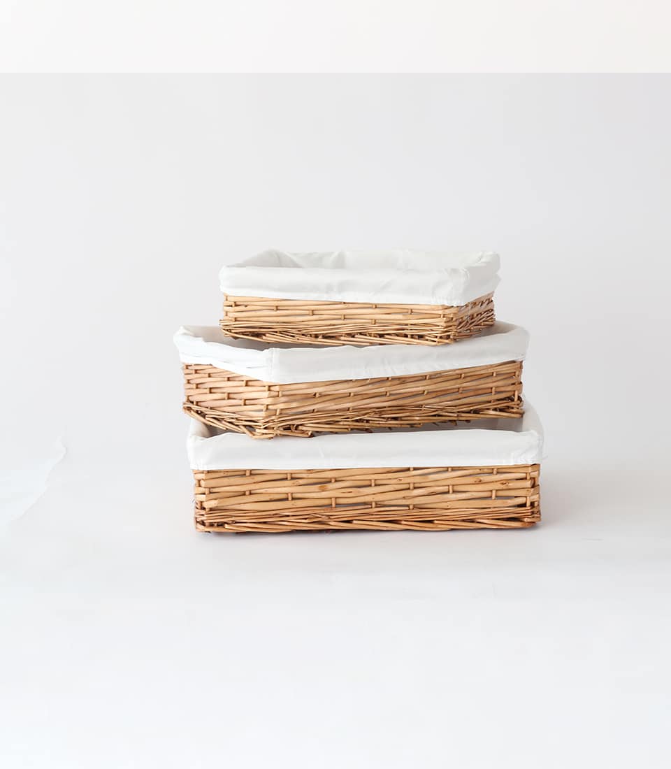 Stacked natural wicker baskets with white cloth linings in three graduated sizes