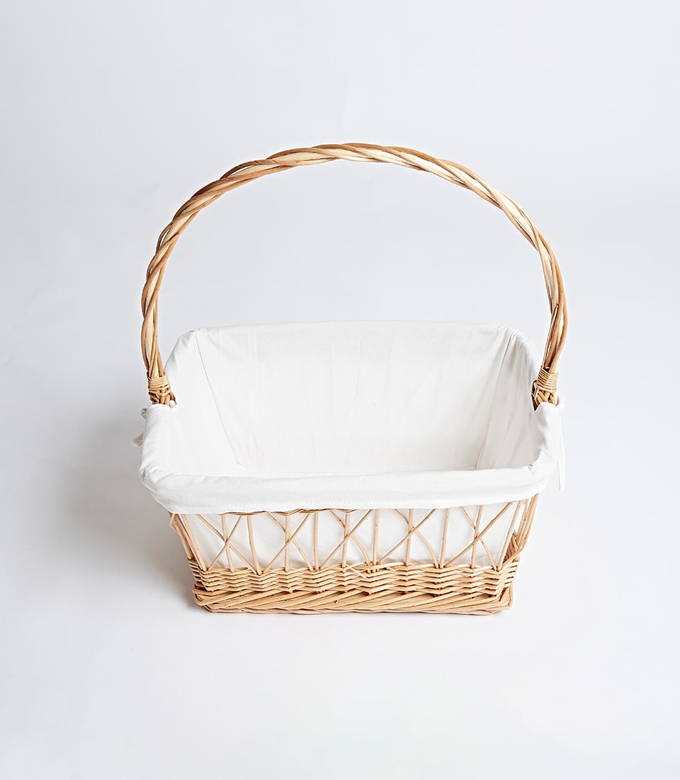 Light brown wicker basket with arched handle and white fabric liner for luxury gift hampers