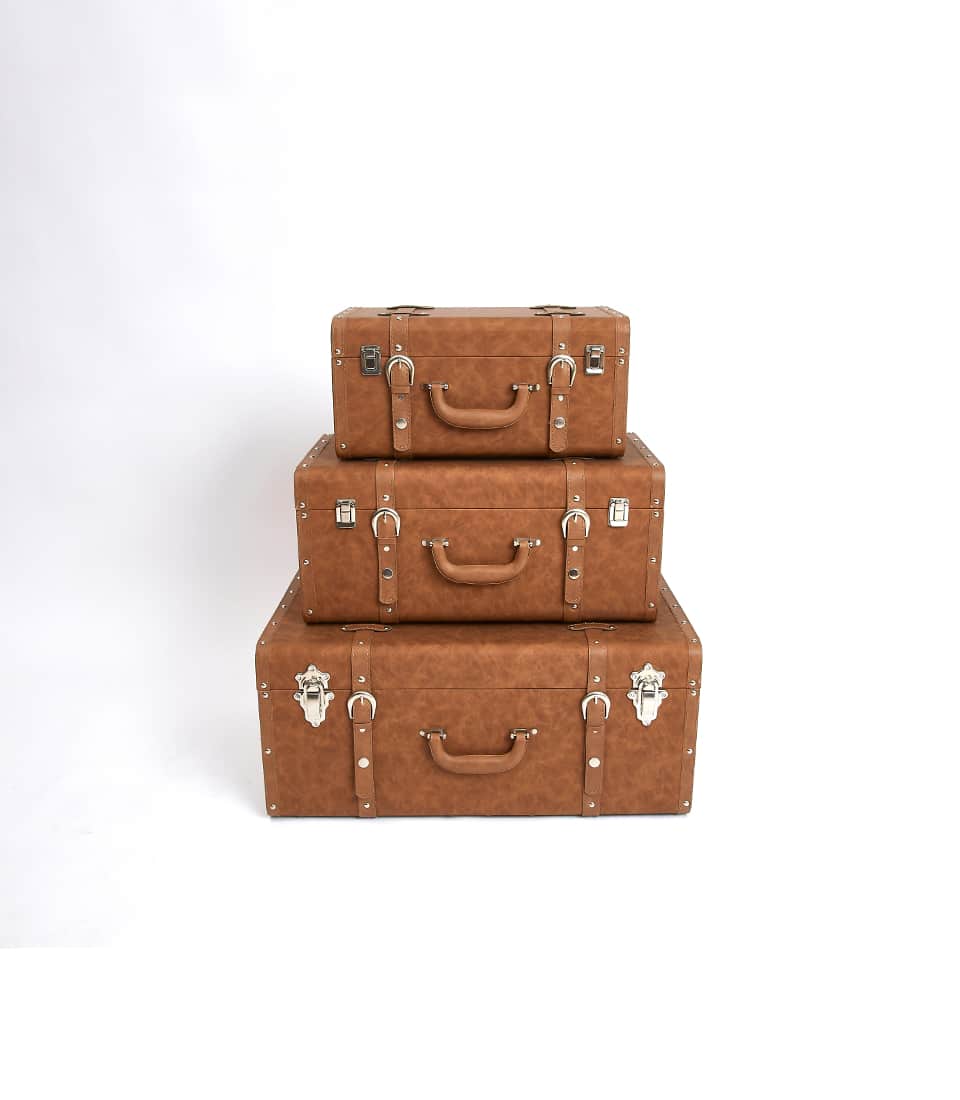 Stacked vintage leather suitcases in light brown with dark straps and silver hardware