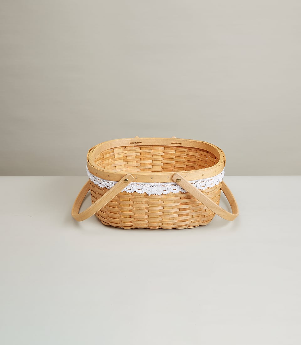 Light woven wicker basket with wooden handles and white lace trim for luxury gift presentation