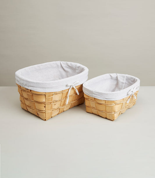 Woven wooden baskets with white fabric liners and ribbon bows for luxury gift hampers