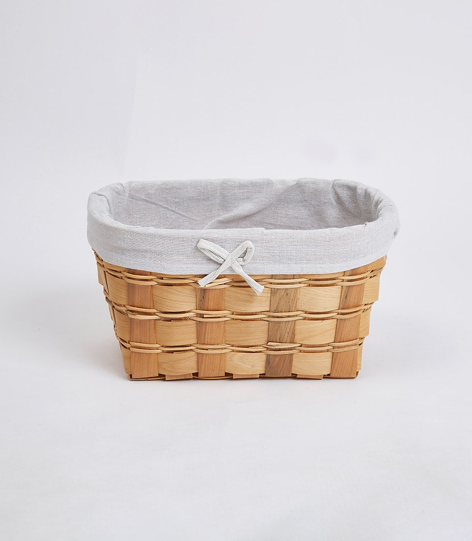Natural woven wooden basket with light grey linen interior and delicate bow detail