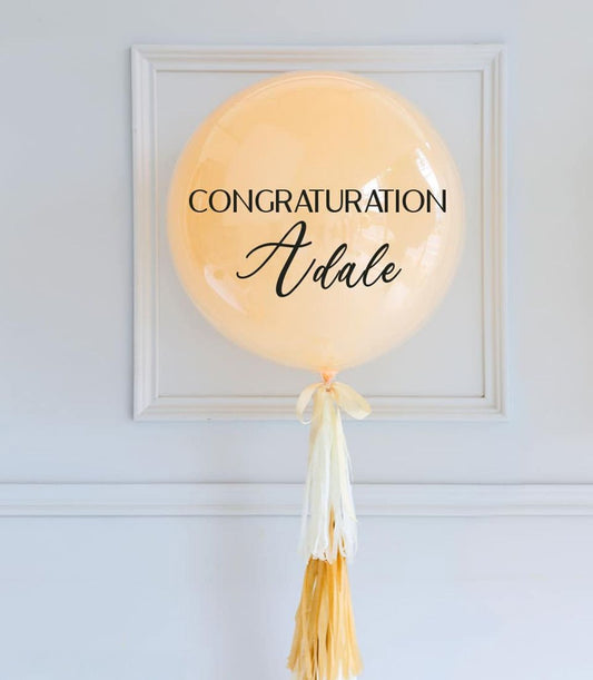 Personalised peach congratulations balloon with cream tassel and custom name in script
