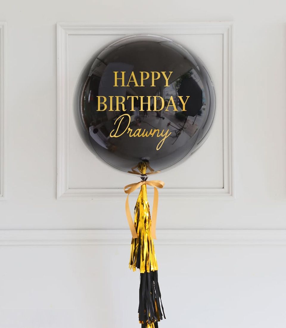 Black birthday balloon with gold happy birthday lettering and matching tassel, elegant celebration gift