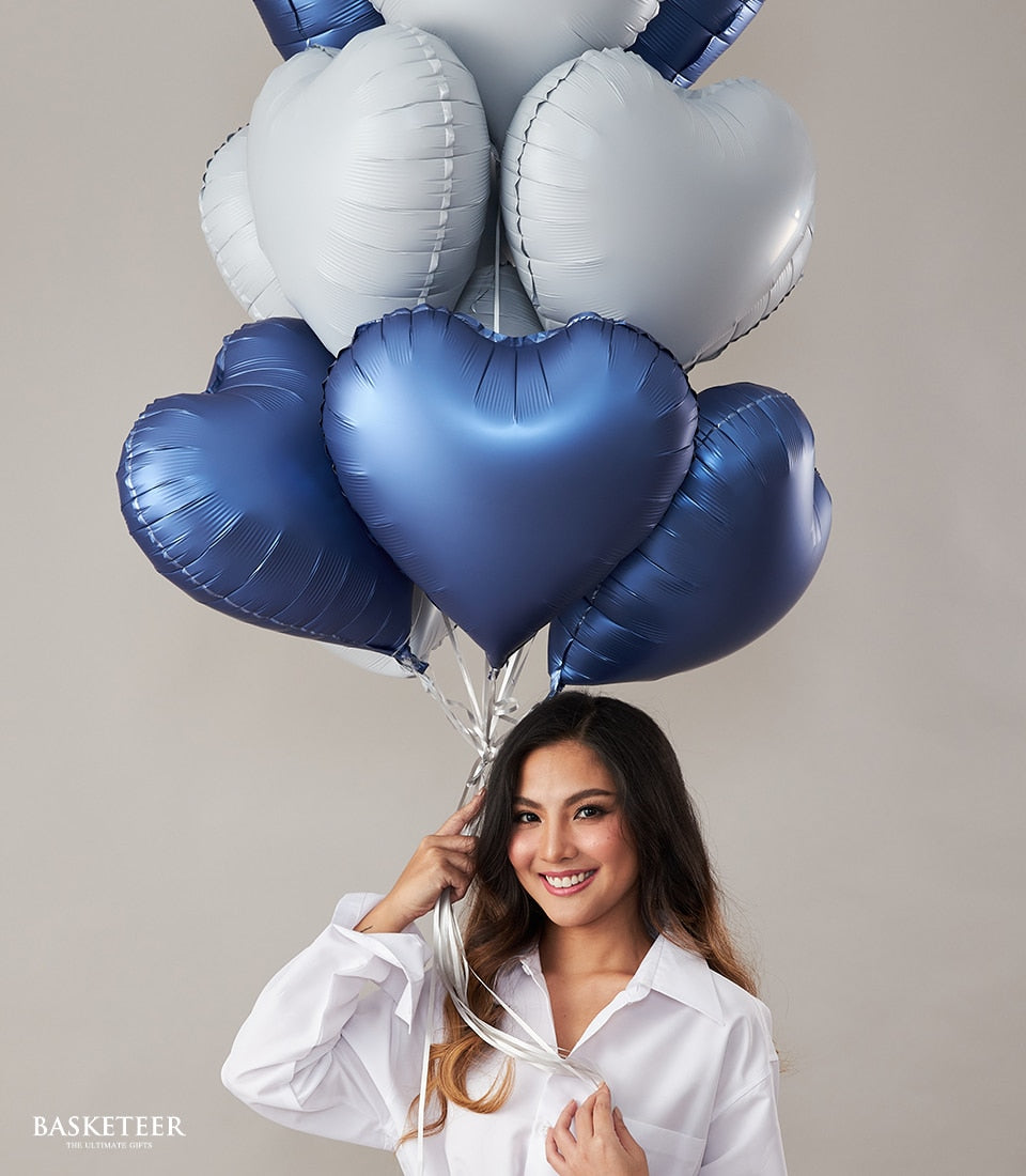 Young woman holding romantic blue and silver heart-shaped balloon bouquet for celebrations