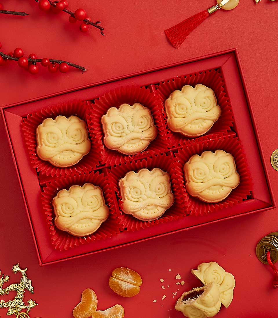 Festive red gift box of six golden mooncakes with dragon lion motifs, mandarin oranges and Chinese coins for Chinese New Year