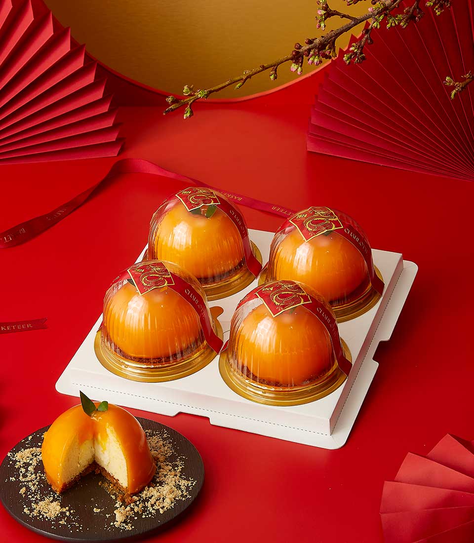 Creamy Mandarin Delight cakes for Chinese New Year, orange-shaped Charlotte Bakery desserts with red ribbon packaging on