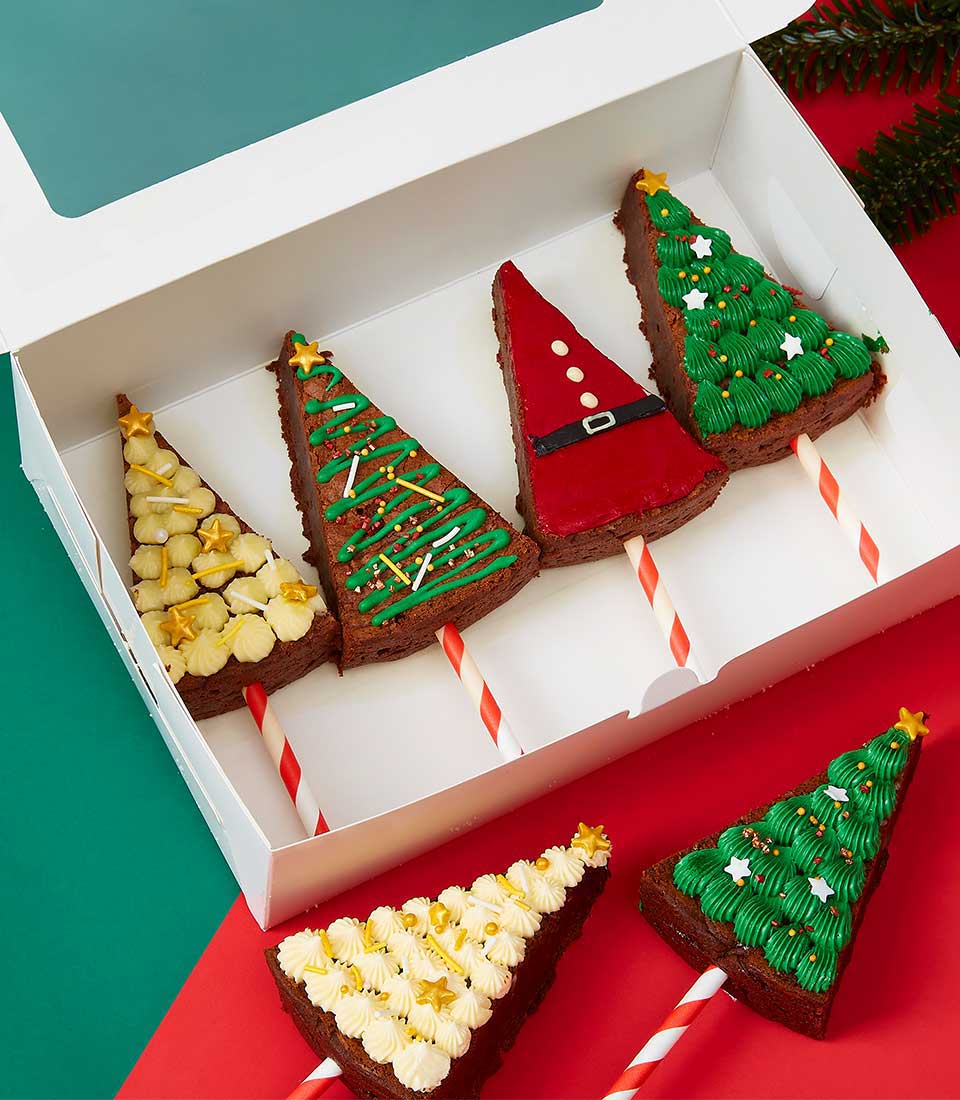 Festive Christmas tree brownie pops with gold stars, Santa-themed red icing, and green piped frosting in gift box