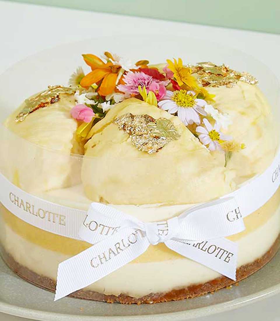 Royal Durian Crown layered cheesecake with gold leaf, fresh flowers, and creamy mousse topping in gift box