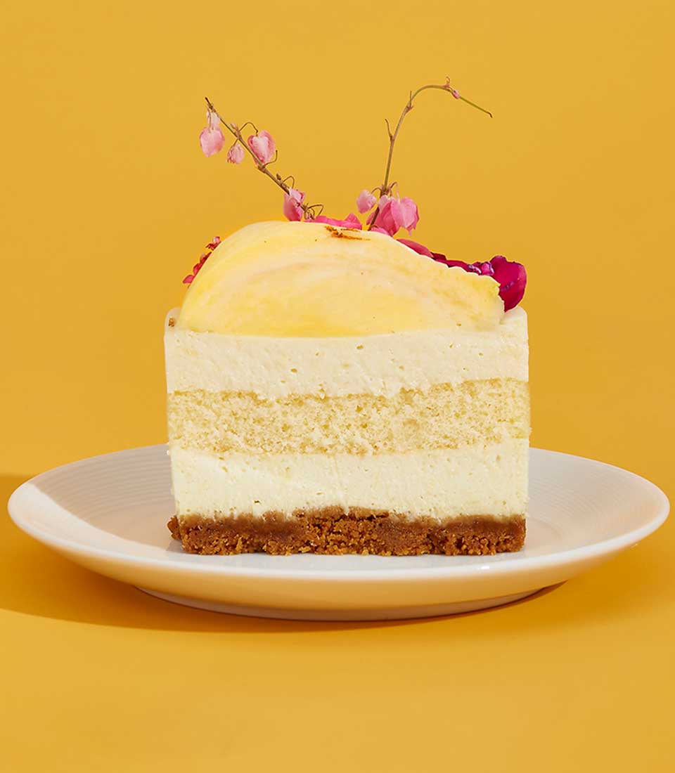 Royal Durian Crown Cake slice with layered sponge, creamy filling, and delicate pink floral garnish