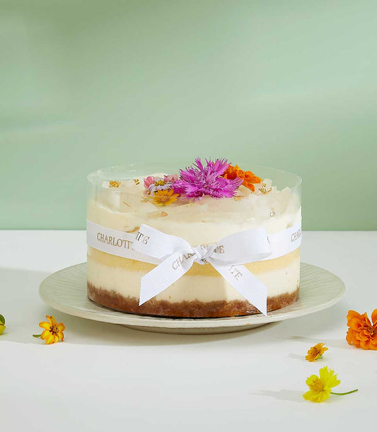 Light and creamy layered cheesecake with fresh flowers and gold leaf, artisan celebration cake from Charlotte Bakery