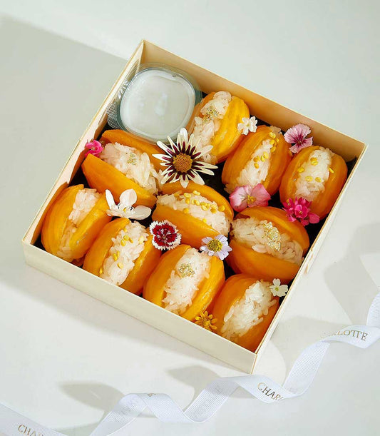 Luxury mango sticky rice gift set with twelve servings, edible flowers, and coconut sauce in wooden box