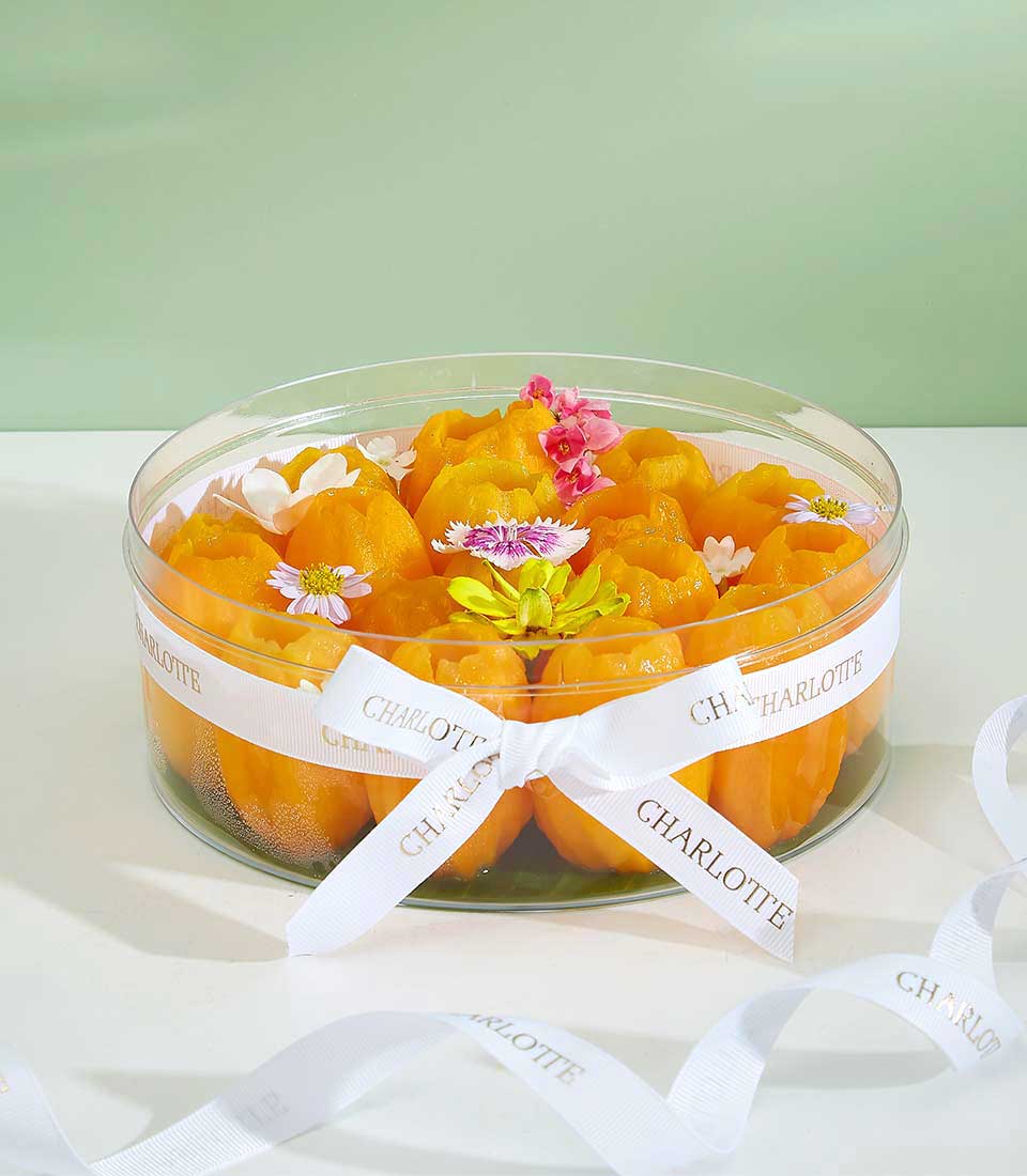 Peeled Mayongchid tropical fruit desserts in clear gift container with fresh flowers and Charlotte Bakery ribbon