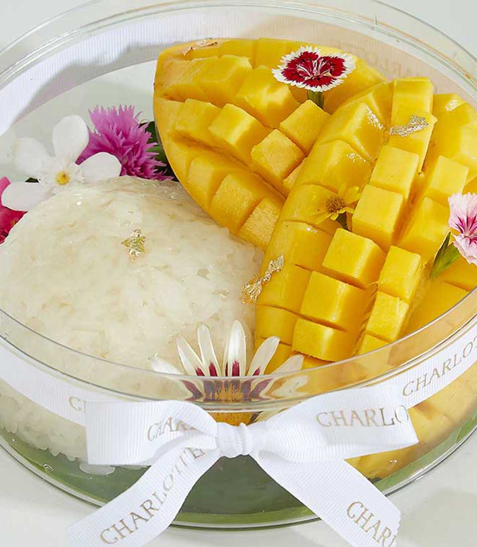 Luxury Thai mango sticky rice dessert with gold leaf and fresh flowers in elegant gift box