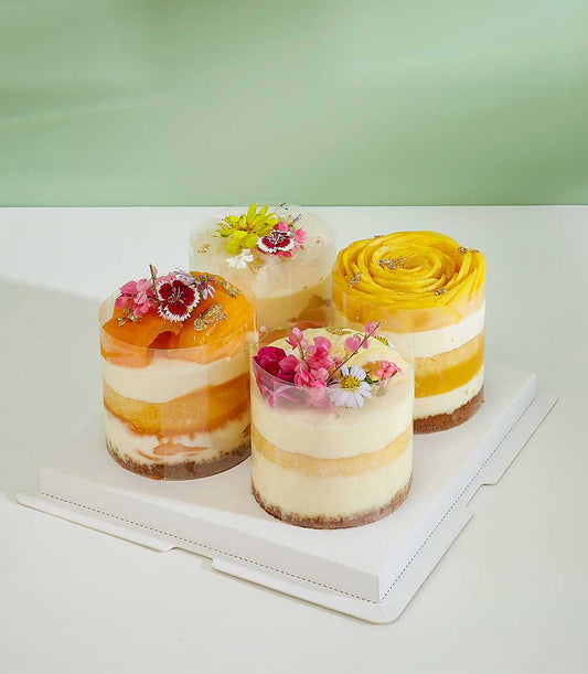 Mini tropical layer cakes with fresh mango, cream, and edible gold in clear gift containers