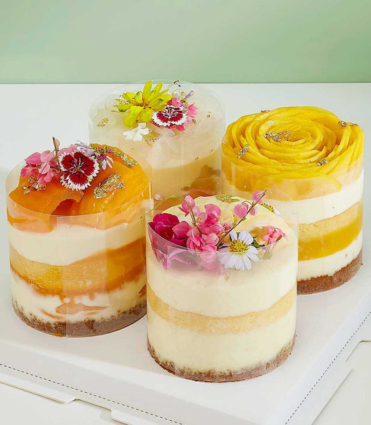 Tropical layered mini cakes with fresh mango, peach, and edible gold in clear cups from Charlotte Bakery