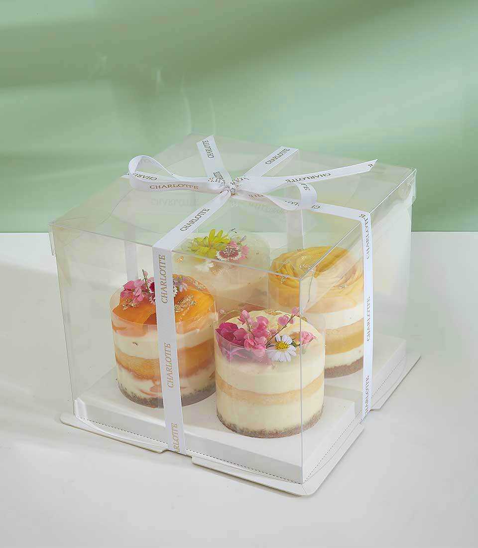 Mixed tropical layer mini cakes with fresh flowers and gold leaf accents in gift box