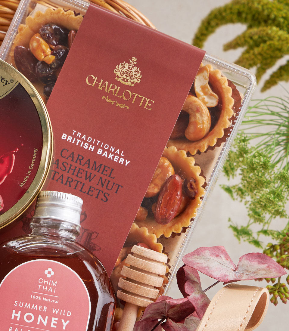 Gourmet gift basket with caramel cashew tartlets, wild honey, and artisan treats in woven basket
