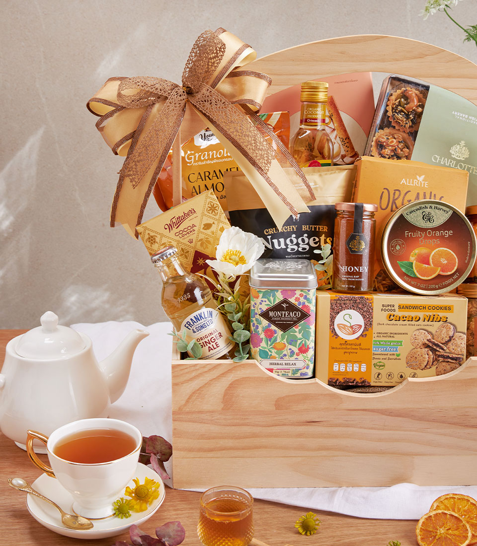 Premium gourmet hamper with organic tea, honey, nuts and artisan cookies in wooden gift box with gold ribbon bow