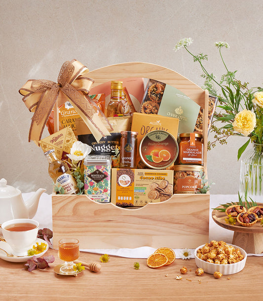 Gourmet gift hamper with organic pantry staples, nuts, herbal tea, and artisan cookies in wooden box