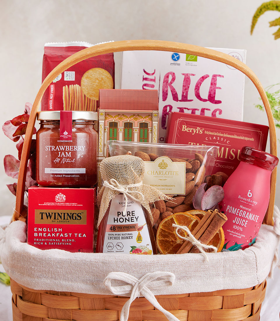 Woven hamper with English breakfast tea, strawberry jam, honey, almonds, and wellness snacks in cream linen and twine
