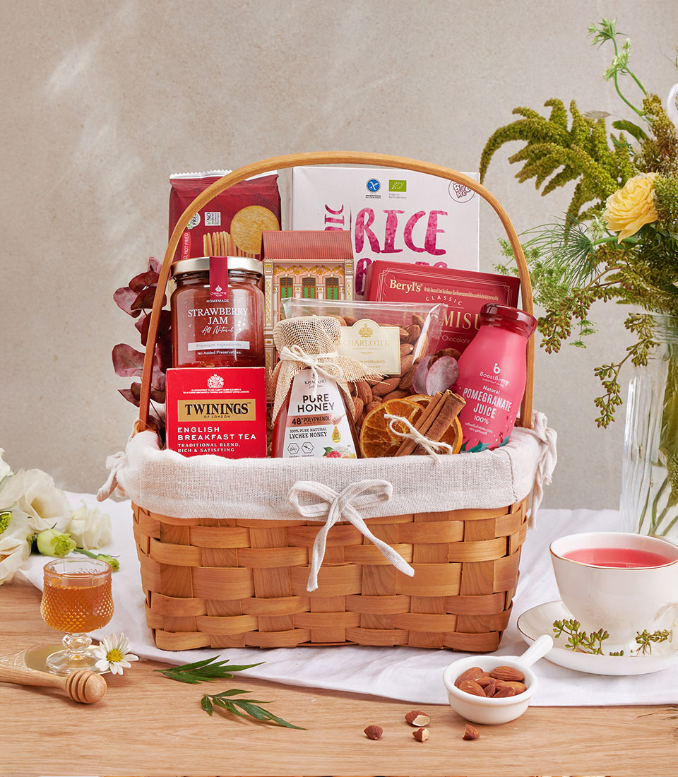 Woven gift basket with English breakfast tea, strawberry jam, honey, almonds, and gourmet wellness treats