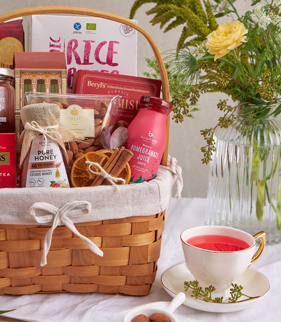 Woven gift basket with organic rice, tiramisu chocolate, almonds, pomegranate juice, honey, and dried citrus, styled with