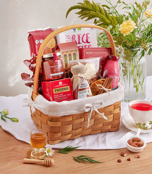 Woven gift basket with English breakfast tea, strawberry jam, lychee honey, and gourmet snacks