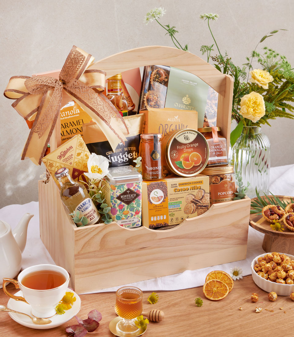 Wooden hamper filled with gourmet cookies, nuts, premium tea, organic honey and artisan pantry goods with gold ribbon