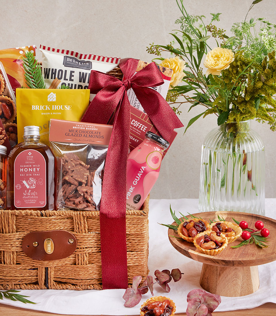 Woven wicker gourmet gift basket with whole wheat chips, honey, chocolate almonds, coffee, and artisan treats, tied with