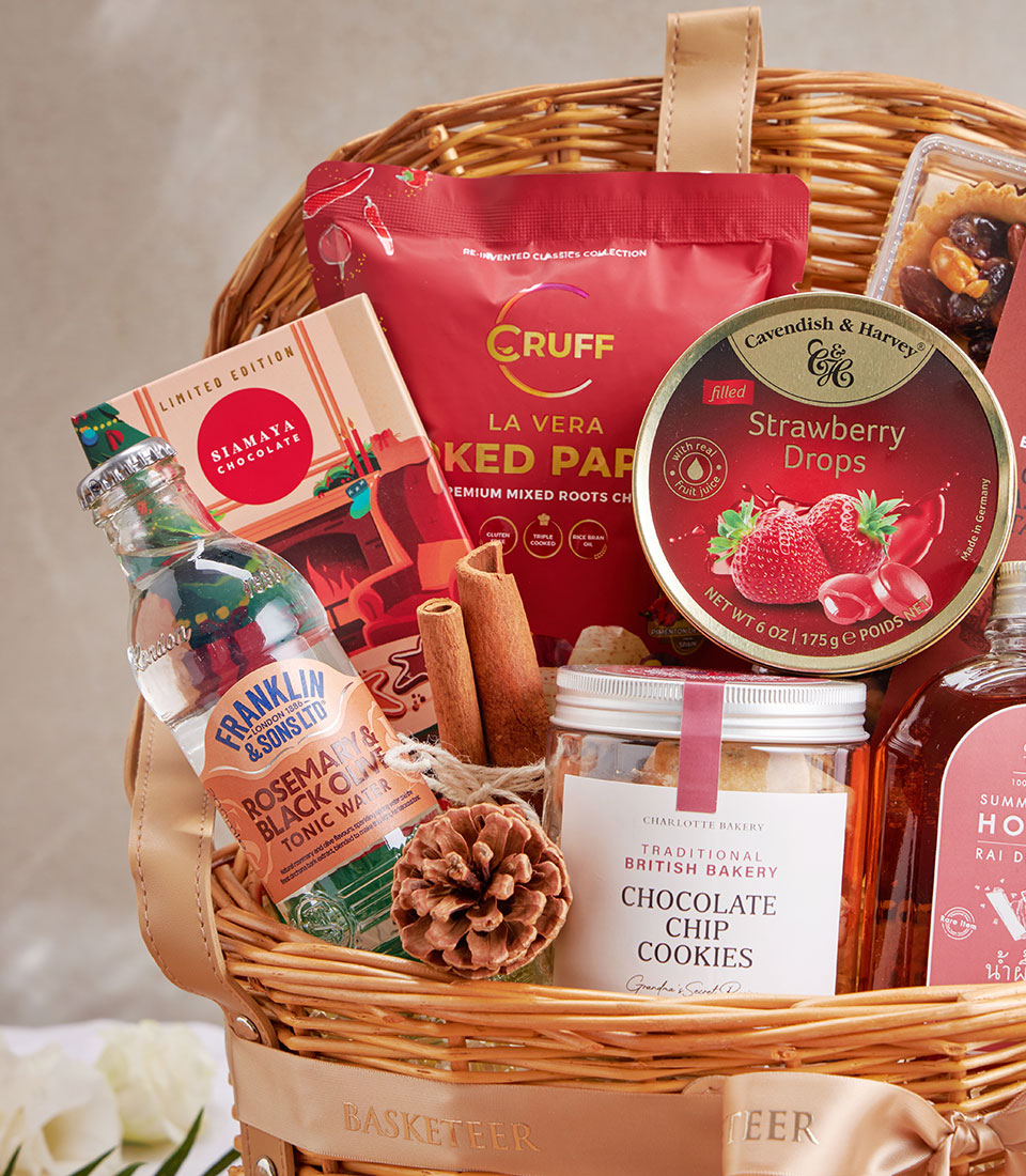 Woven wicker hamper with chocolate chip cookies, gourmet treats, and artisan selection tied with gold satin ribbon