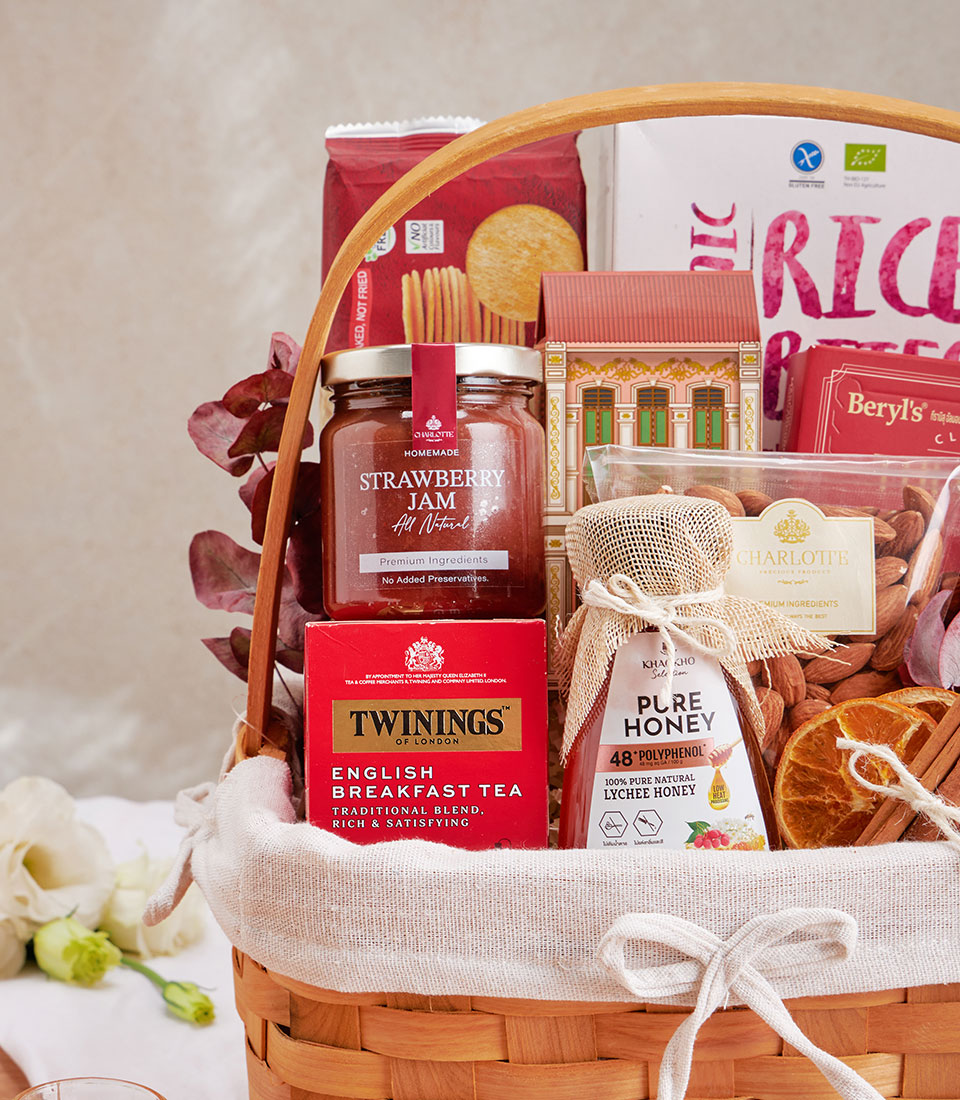 Woven gift basket with English breakfast tea, strawberry jam, lychee honey, crackers, and almonds for health-conscious