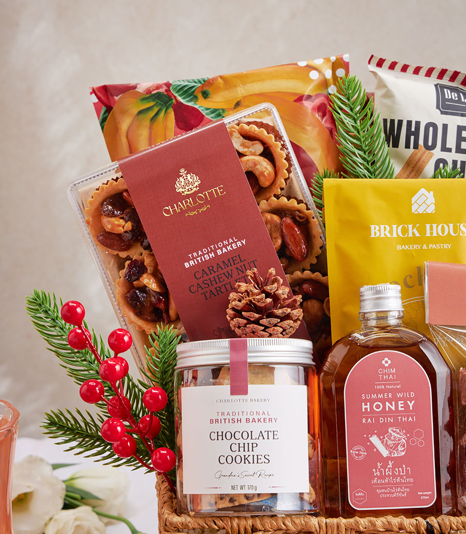 Gourmet gift hamper with artisan cookies, honey, and caramel cashew tartlets in woven basket